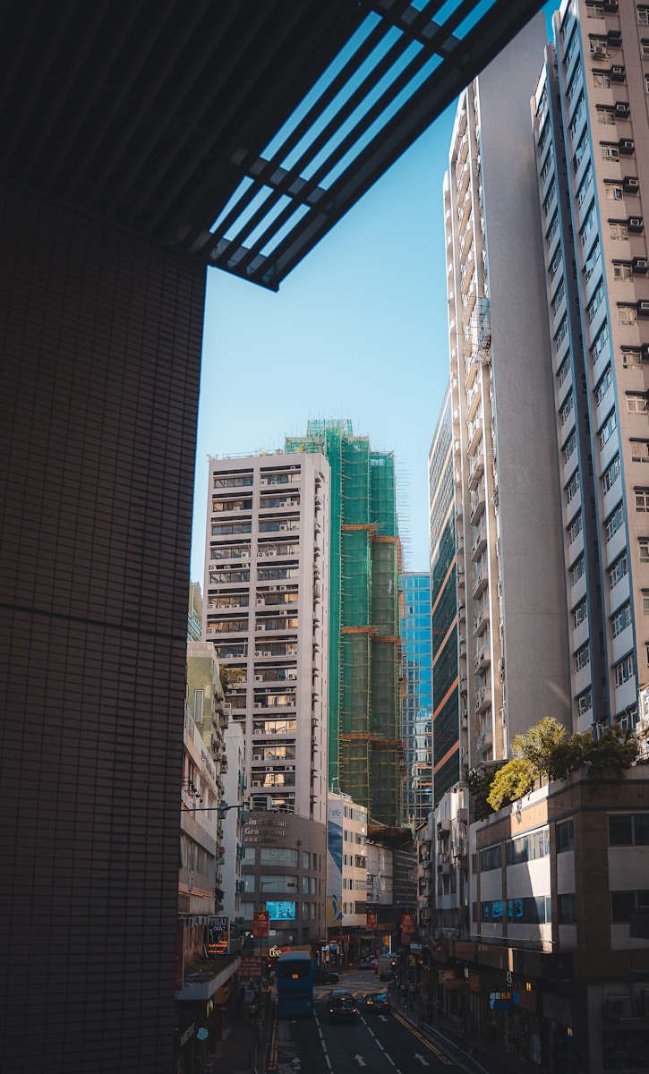 Tall buildings line a street with cars and blue sky.